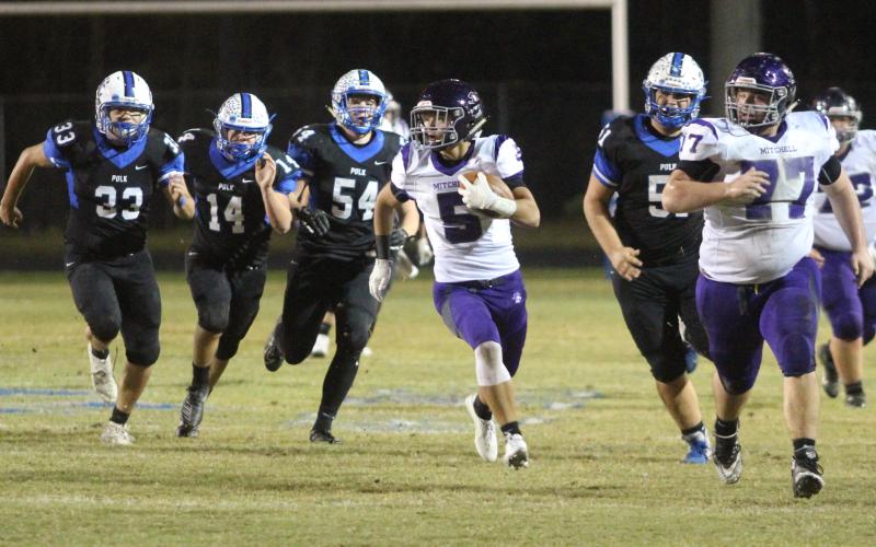 Mitchell junior Ty Pitman (No 5) breaks away from Polk defenders behind lead blocker and senior Lathan Adkinson (No. 77) Friday, Nov. 1, during the Mountaineers’ 33-0 win over the Polk Wolverines in Columbus. Pitman caught one pass for 15 yards and a touchdown in the game. (MNJ/Brandon Roberts)
