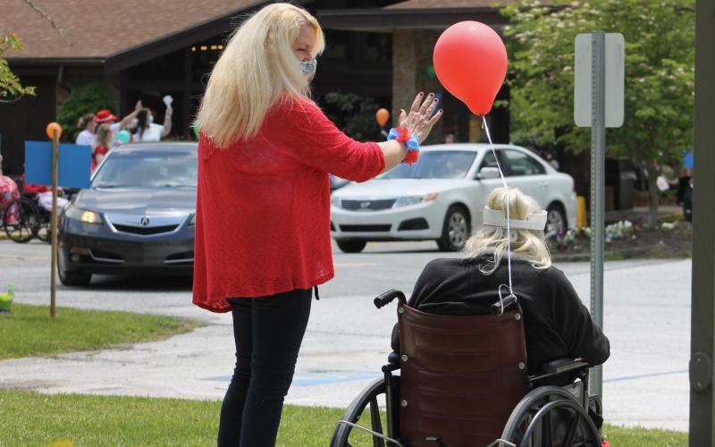 Brian Center Activities Director Debbie Finley, left, and resident Mary Jarvis wave at cars passing by Thursday, May 14, during a drive-thru parade. (Photos by Juliana Walker/MNJ)
