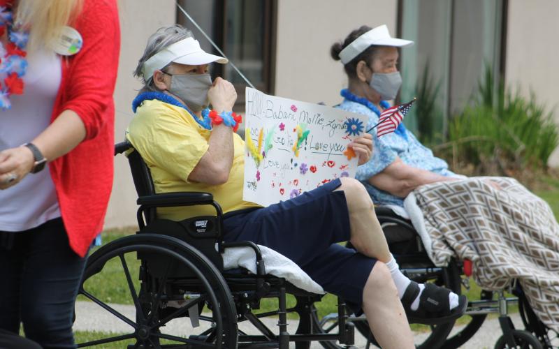 A Brian Center Resident enjoys the parade along with a hand-made sign with names of family members and the words "Love you." (Photos by Juliana Walker/MNJ)