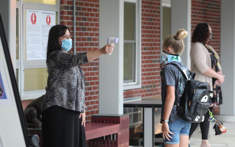 Bowman Middle School Counselor Crystal Robinson takes a student's temperature with a non-contact infrared thermometer as students arrive at school on Monday, Aug. 17. Students went back into schools for the first time since March and had two temperature checks before entering the buildings. (MNJ Photo/Juliana Walker)