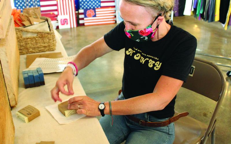 Kendall Chandler, owner and developer of The Quill and Honey, wraps up soap bars to prepare them for sale Friday, July 31 during the Rock Hound Craft and Vintage Market at Cross Street Commerce Center. Chandler came to the show from Forks of Ivy. (MNJ photo/Cory Spiers)