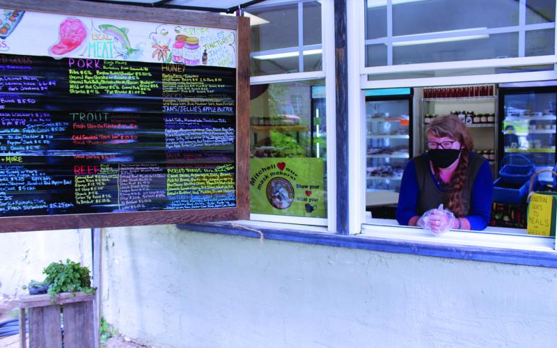 Just Local Market Owner Megan Bell smiles underneath her mask as customers approach the window of her store to place an order on Thursday, Aug. 27. Just Local, located in Bakersville, sells fresh products from area farmers, many of which are from Mitchell County.  (MNJ photo/Cory Spiers)