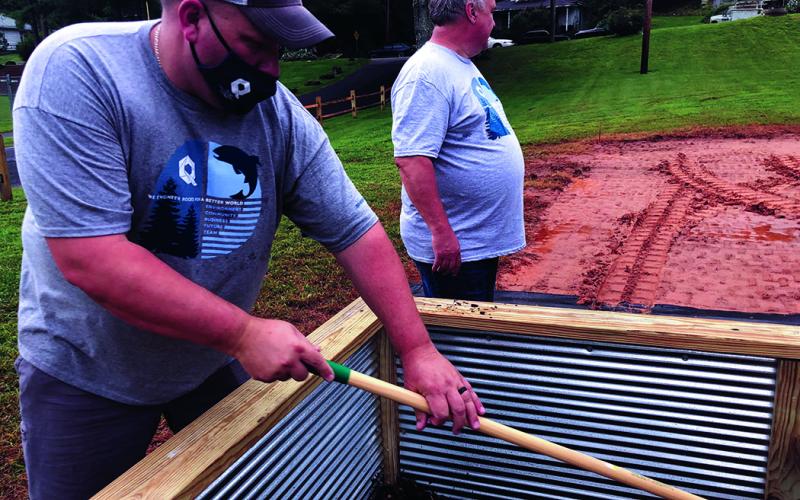 Chris Gentry of The Quartz Corp. uses a rake to smooth out soil in one of the new community garden beds in Riverside Park. The installation of the beds was part of The Quartz Corp.’s Volunteer Day. (Submitted photo)