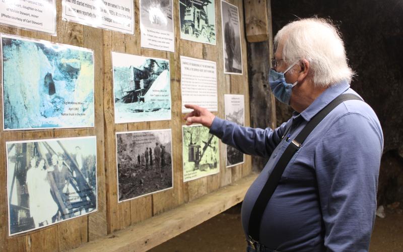 Emerald Village Owner Alan Schabilion points to historic photos of old mining operations displayed inside the Bon Ami Mine in Little Switzerland. (MNJ photo/Juliana Walker)