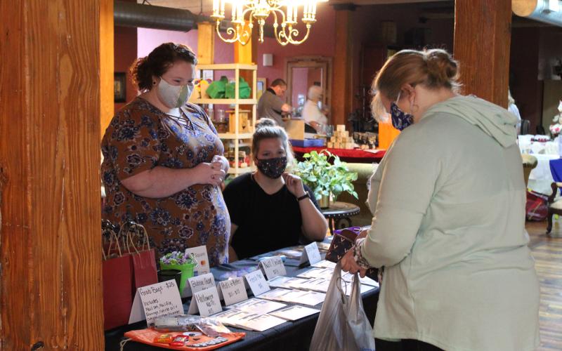 Dry nail polish vendor Courtney Sayles speaks about her product through her mask to a potential customer during the Spruce Pine Fall Festival at the Cross Street Commerce Center on Saturday, Oct. 10. The event is usually held in the Burnsville Town Center, which is currently closed due to the ongoing pandemic. The festival featured more than 40 vendors selling a variety of fall-themed items. (MNJ photo/Juliana Walker)
