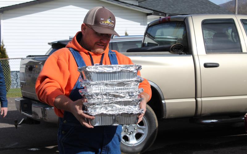 Brian Holloway, a volunteer with the Repairer of the Breach Ministries, helps load trays of barbecue into vehicles heading out into the community for delivery. The ministry provided meals to 450 families in need. A slew of local volunteers were instrumental in the delivery and preparation efforts. (MNJ photo/Juliana Walker)