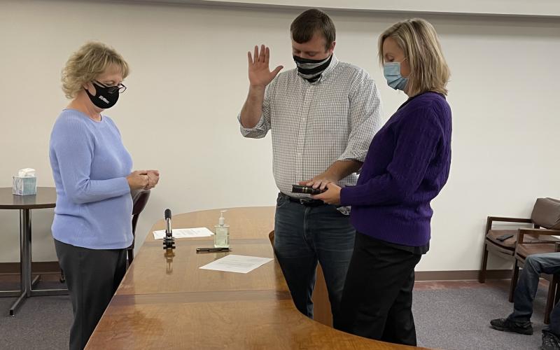 Newly-elected Mitchell County Commissioner Brandon Pittman is sworn in by Mitchell County Register of Deeds Kathy Laws as his wife Lisa Pittman helps him by holding the Bible on Monday, Dec. 7. The new board met later that day and approved changes, including holding two monthly meetings. (MNJ photo/Juliana Walker)