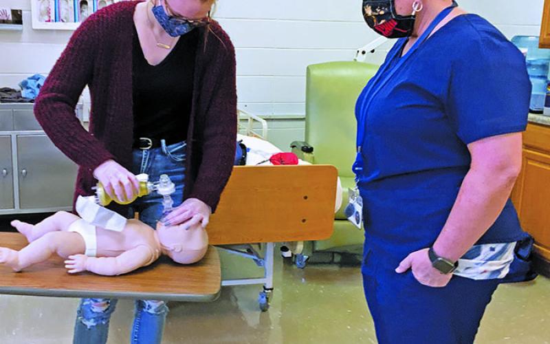 Shannon Tipton of Hospice, Palliative and CAP of the Blue Ridge looks on as Mitchell High School students perform adult and infant CPR. Tipton helped 35 students earn their CPR certification through hands-on training and testing. (Submitted)
