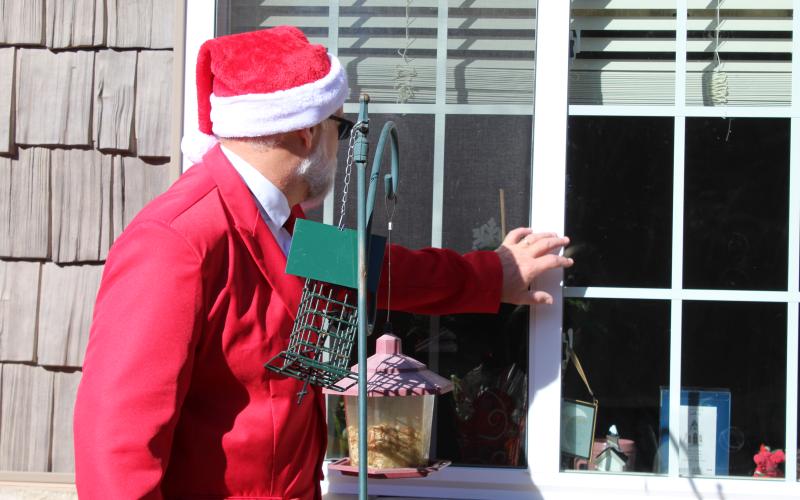 Spruce Pine Police Chief Bill Summerlin reaches out to say hello to a resident of one of the county’s assisted living facilities on Friday, Dec. 18. Summerlin, dressed as Santa Claus, went around and spread holiday cheer via the windows, due to the ongoing pandemic. (MNJ photo/Juliana Walker)