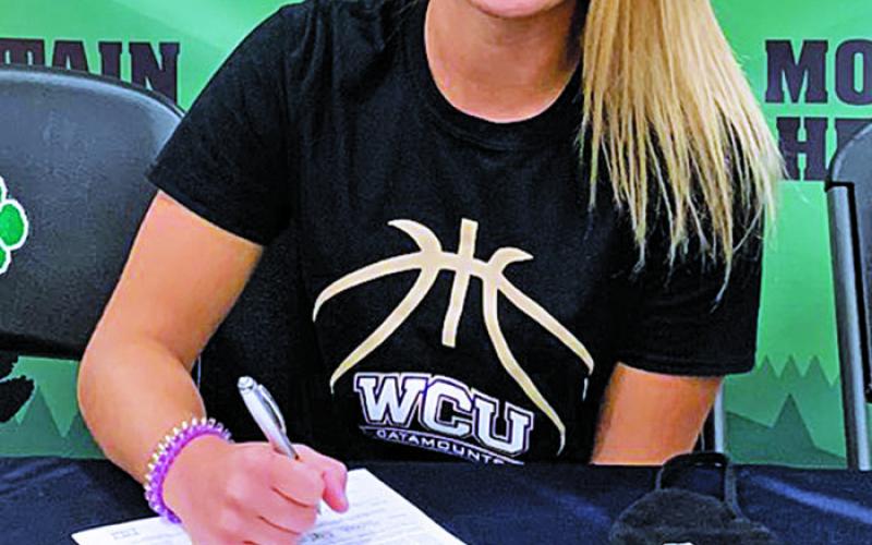 Heritage senior Hannah Tipton puts pen to paper on her commitment to Western Carolina. Her grandfather was instrumental in Mitchell County recreation league sports. (Submitted)