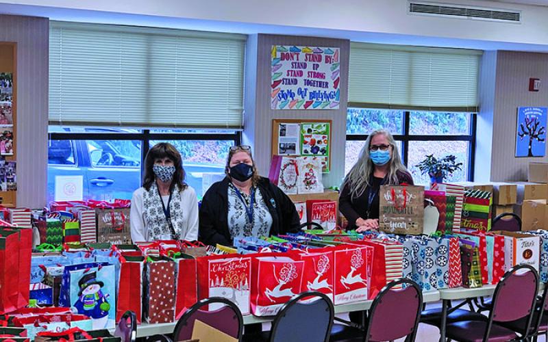A trio of Santa for Seniors volunteers sit behind scores of gifts that eventually made their way to area seniors in need of something special during the holiday season. Pictured, from the left, is Wynne Strickland, Billie Lister and Danielle Chabot. (Submitted photo)