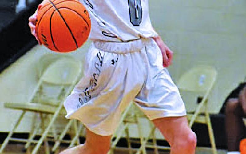 Senior guard Jeremy Sparks dribbles up the court and surveys the situation as he prepares to make a pass during a home game against Owen on Wednesday, Feb. 3. (Photo by Tessa Taylor)