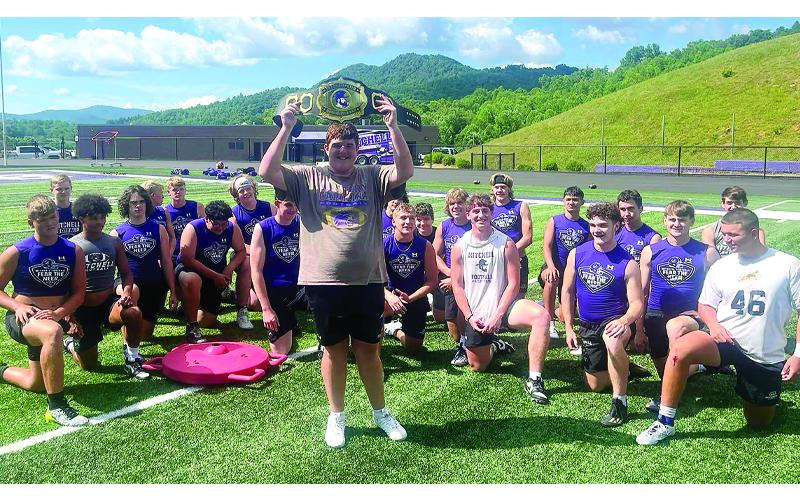 The inaugural winner, Bryce Miller #60, holds the belt in front of the Mountaineers football team.