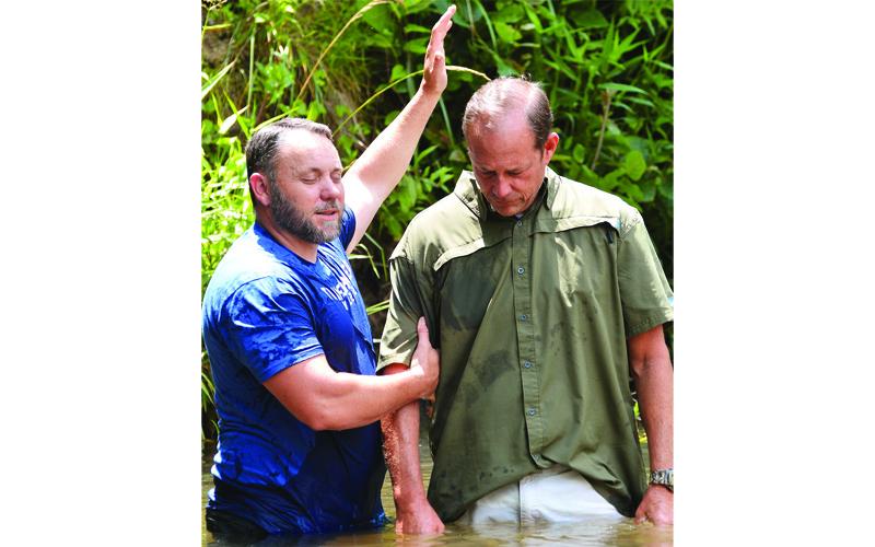 Submitted photo The Rev. Nathan Silver, left, of Grassy Creek Baptist Church prays over Kelly Pitman as he prepares to baptize him in Grassy Creek.