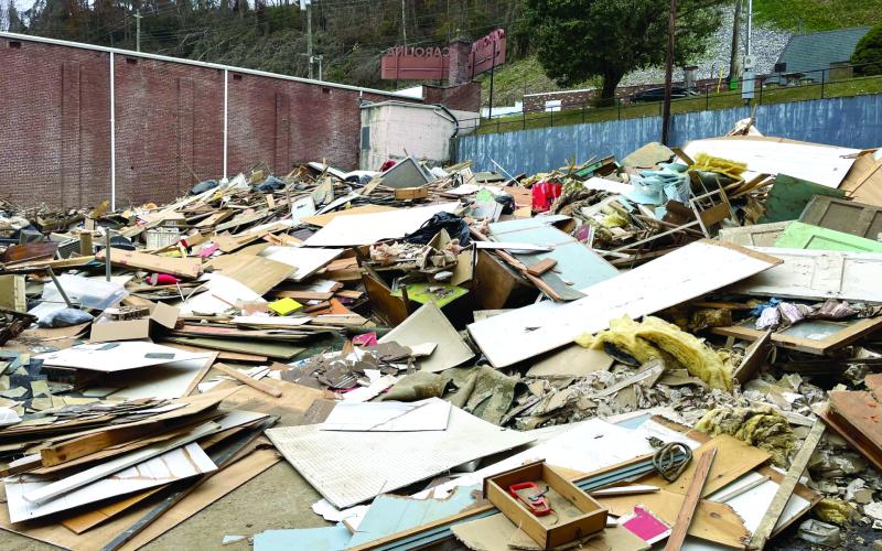 MNJ photo/Mariel Williams.  Unsorted debris fills the parking lot next to the old Carolina Theater on Lower Street (Locust Street) in Spruce Pine. In order to get picked up and properly disposed of, flood debris is supposed to be sorted into three categories: wood/tree waste, construction debris and white goods (appliances). Those piles should be stacked on the right-of-way of state and town roads.