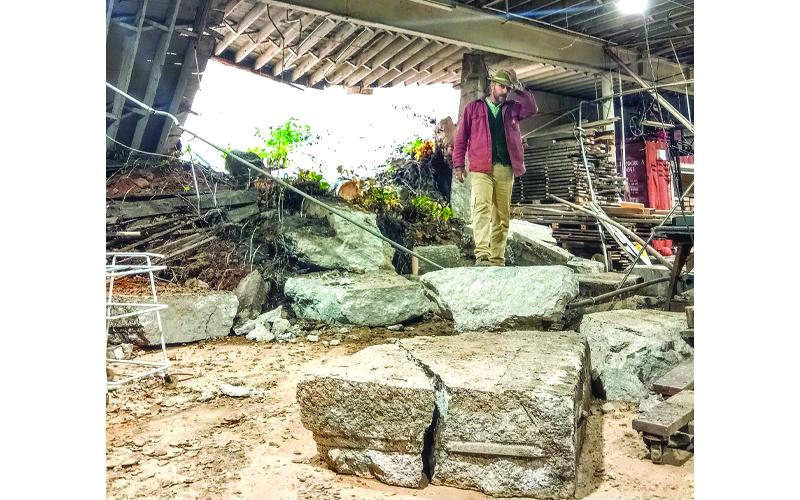 Submitted photo.  Owner Chris Nash stands in the landslide wreckage that smashed into Mitchell Lumber Company in September.