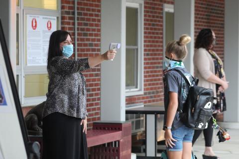 Bowman Middle School Counselor Crystal Robinson takes a student's temperature with a non-contact infrared thermometer as students arrive at school on Monday, Aug. 17. Students went back into schools for the first time since March and had two temperature checks before entering the buildings. (MNJ Photo/Juliana Walker)