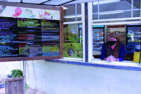 Just Local Market Owner Megan Bell smiles underneath her mask as customers approach the window of her store to place an order on Thursday, Aug. 27. Just Local, located in Bakersville, sells fresh products from area farmers, many of which are from Mitchell County.  (MNJ photo/Cory Spiers)