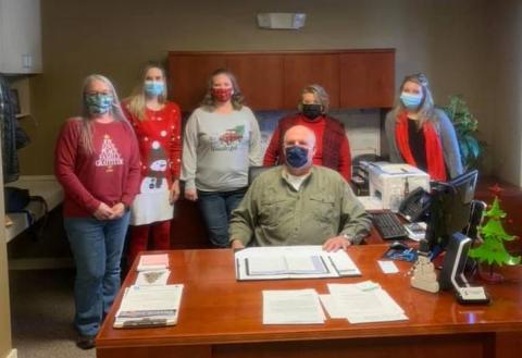 Richard Canipe (seated) is surrounded by his co-workers in his office earlier this month. Canipe announced that he will retire as town manager at the end of the month. Darlene Butler (left) will take over the position after serving more than two decades as town clerk. (Photo courtesy of the Town of Spruce Pine)