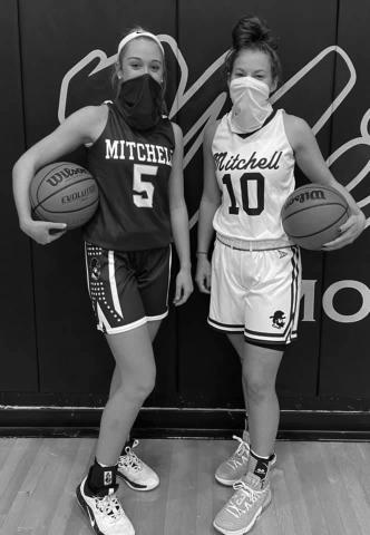 Mitchell High School junior Chandra Jenkins (left) and senior Marley Cloer (right) pose in the school gym to show off the new uniforms for the girls’ basketball team. The new purple jersey features block lettering on the front and the new white jersey features cursive lettering. The team, which is coming off of a 22-6 campaign, will start official organized practices this month and will begin a shortened season in January. (Submitted photo)