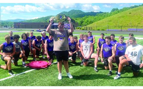 The inaugural winner, Bryce Miller #60, holds the belt in front of the Mountaineers football team.