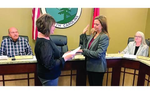 MNJ photo/Mariel Williams.  Attorney Beth Holmes, center right, is sworn in as a member of the Spruce Pine Town Council, while Mayor Phillip Hise (left) and Town Manager Darlene Butler (right) look on. 
