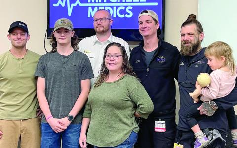 MNJ Photo/Mariel Williams.  Mitchell Medics honored four employees recently for their efforts to save a teenager in a medical crisis the morning Hurricane Helene knocked out communications in Mitchell County. From left are Dr. Gabriel Cade of Blue Ridge Regional Medical Center, patient Devon Hughes, and Mitchell Medics staffers Alex Brown, Jared Stickle and Evan Stern, holding Millicent Stern.