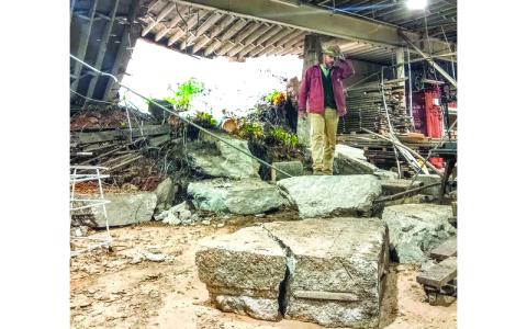 Submitted photo.  Owner Chris Nash stands in the landslide wreckage that smashed into Mitchell Lumber Company in September.