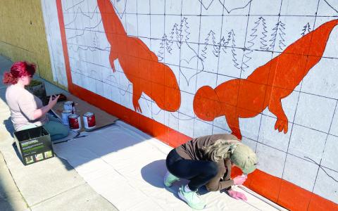 MNJ Photo/Mariel Williams.  Local artists Katie Elkins, left, and Anita Blackwell work on a mural advertising the first-ever Hellbender Festival, which is scheduled for Labor Day weekend. Elkins, who is also the media and marketing specialist for Downtown Spruce Pine, drafted the design for the mural. 