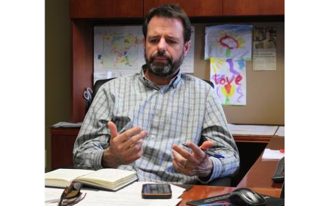 MNJ Photo/Mariel Williams.  New Town Manager Daniel Stines reflects on the challenges facing Spruce Pine’s recovery, surrounded by artwork donated to his office by his children. 