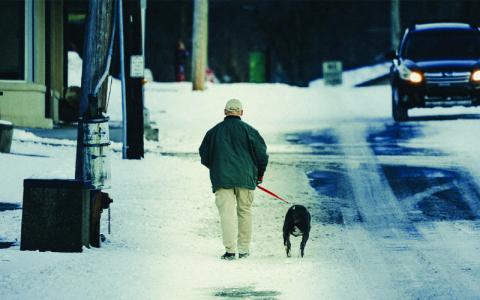 Photo/Joshua McKinney.  A sheet of snow and ice blanketed Mitchell County for the second consecutive weekend on Saturday. While many felt the plummeting temperatures were unfit for man or beast, they didn’t discourage Dr. Marvin Walker from taking a stroll through Spruce Pine with his loyal companion. 