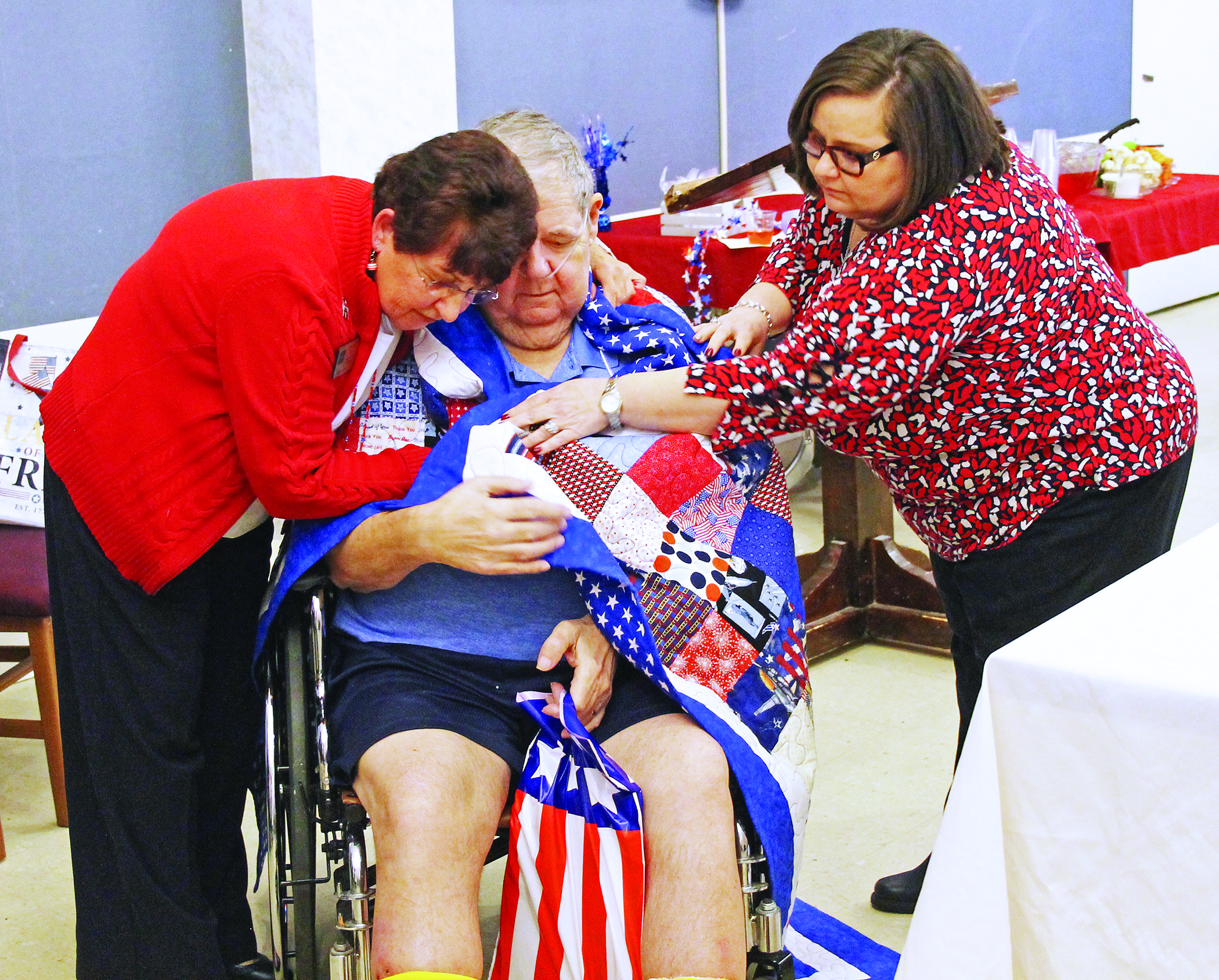 Quilts of Valor volunteer Stamie Cline (left) embraces United States Air Force veteran and Brian Center resident Ephraim “E.K.” Brown as Brian Center Administrator Shelley Tinsley helps wrap Brown in his Quilt of Valor. Brown, 67, is a highly decorated veteran who served more than 20 years in the Air Force, including three tours of duty in Germany. (Cory Spiers/MNJ)