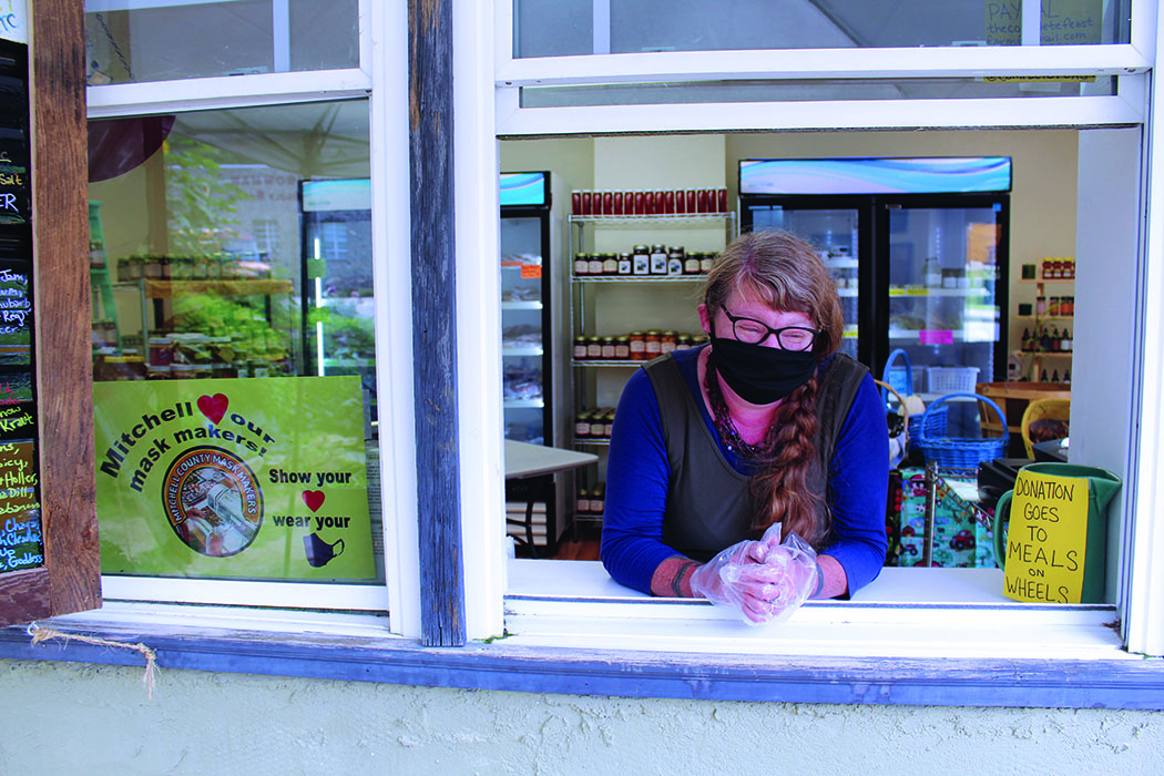 Just Local Market Owner Megan Bell stands in her store’s pickup window ready to help customers. Bell is taking all the necessary precautions during the pandemic including always wearing gloves and a mask when interacting with customers and products. In addition, the pickup window is the only method of shopping available during the pandemic. Bell’s market sells products from local farmers. (MNJ photo/Cory Spiers)