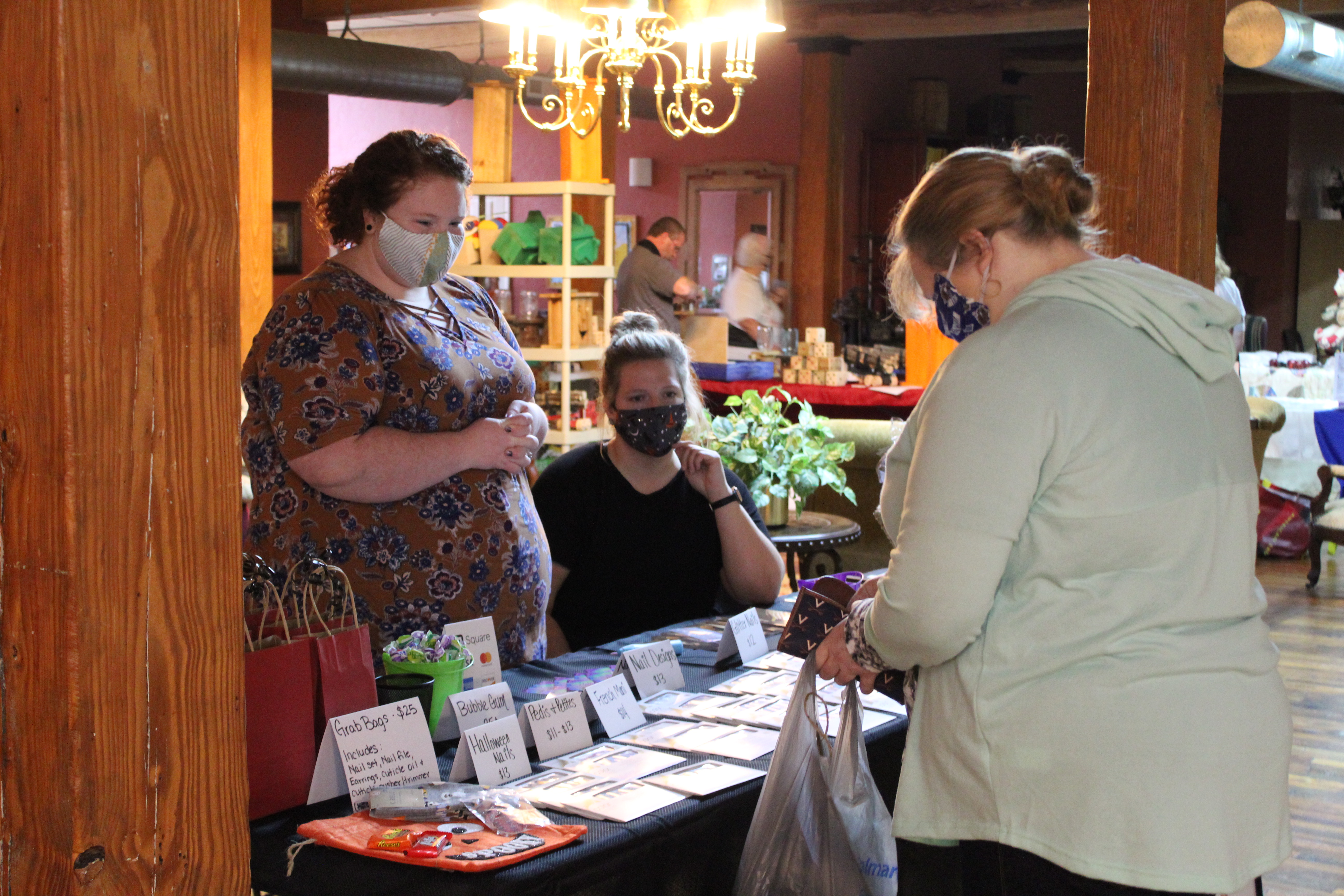 Dry nail polish vendor Courtney Sayles speaks about her product through her mask to a potential customer during the Spruce Pine Fall Festival at the Cross Street Commerce Center on Saturday, Oct. 10. The event is usually held in the Burnsville Town Center, which is currently closed due to the ongoing pandemic. The festival featured more than 40 vendors selling a variety of fall-themed items. (MNJ photo/Juliana Walker) 