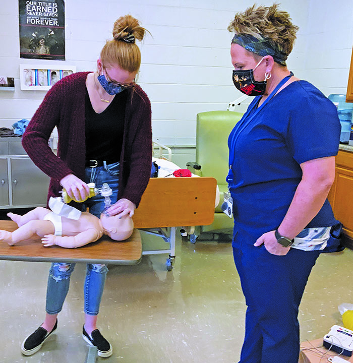 Shannon Tipton of Hospice, Palliative and CAP of the Blue Ridge looks on as Mitchell High School students perform adult and infant CPR. Tipton helped 35 students earn their CPR certification through hands-on training and testing. (Submitted)