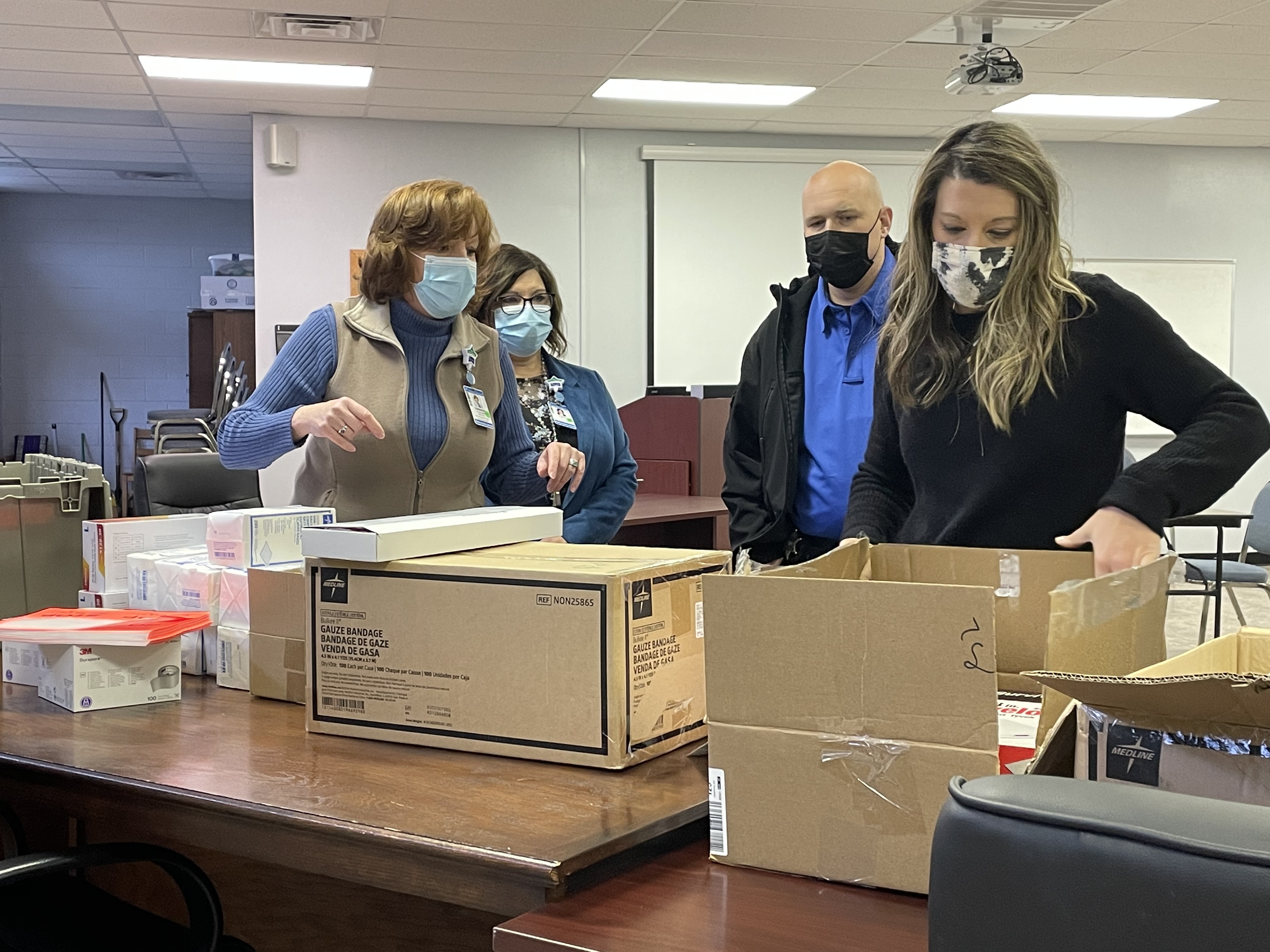 Neill, Hale and Vance look on as Mitchell County School Nurse Elizabeth Sparks unboxes and inspects some of the new Stop the Bleed kits. (MNJ Photo/Juliana Walker)