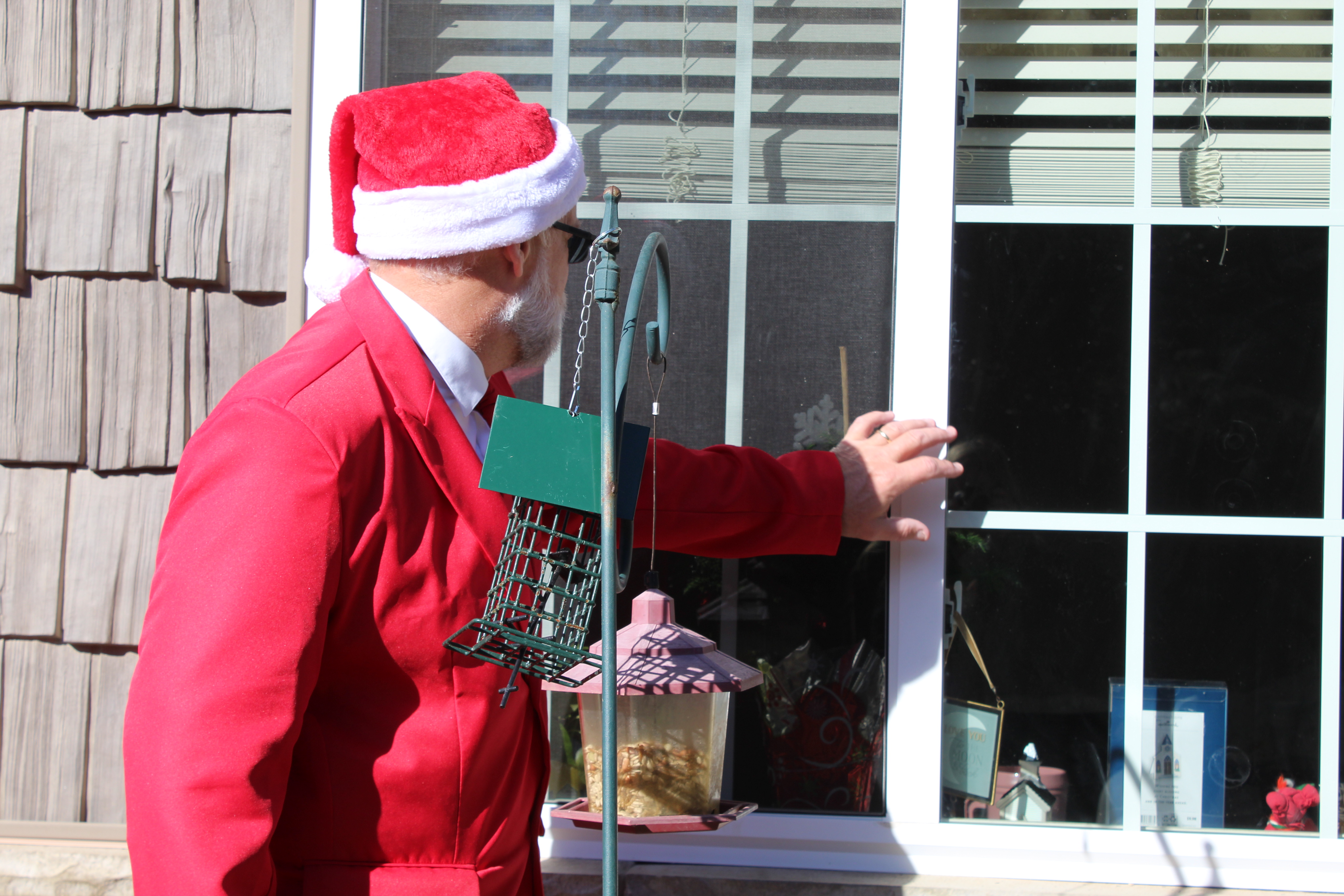 Spruce Pine Police Chief Bill Summerlin reaches out to say hello to a resident of one of the county’s assisted living facilities on Friday, Dec. 18. Summerlin, dressed as Santa Claus, went around and spread holiday cheer via the windows, due to the ongoing pandemic. (MNJ photo/Juliana Walker)