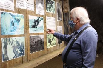 Emerald Village Owner Alan Schabilion points to historic photos of old mining operations displayed inside the Bon Ami Mine in Little Switzerland. (MNJ photo/Juliana Walker)