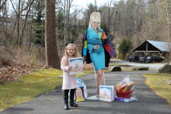 Yancey County resident Magnolia Burleson, 4, poses in Spruce Pine Riverside Park with her Imagination Library book in front of a life-size cut-out of program founder, Dolly Parton. (MNJ photo/Juliana Walker)